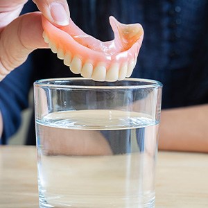 Dentures being placed in a glass of water