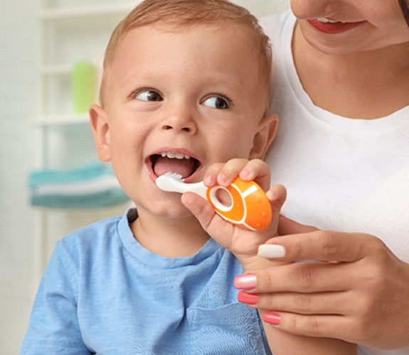 Mother helping young son brush his teeth