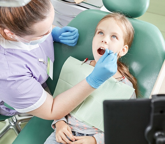 Dentist checking a young girl’s mouth