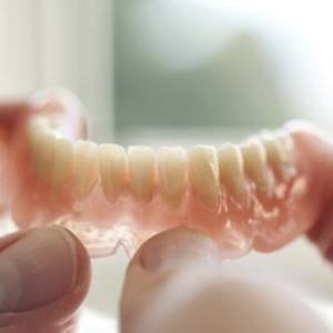 Person holding a lower denture