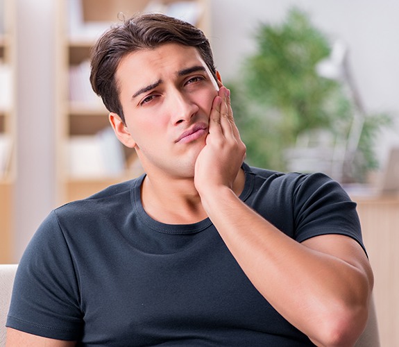 Man in need of emergency dentistry holding his cheek
