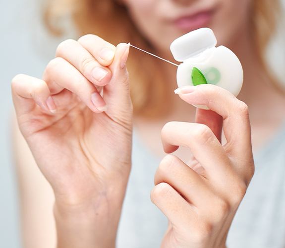 Person flossing to prevent dental emergencies
