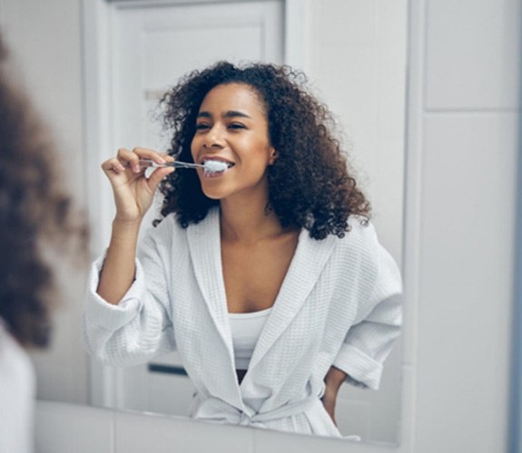 a patient smiling and brushing their teeth