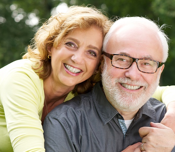 Older man and woman smiling after dental implant supported tooth replacement