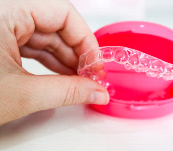 Hand taking Invisalign aligner out of storage case