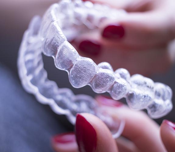 Hand holding a set of Invisalign clear aligners