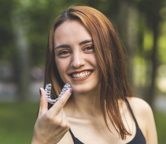 Smiling woman holding an Invisalign tray