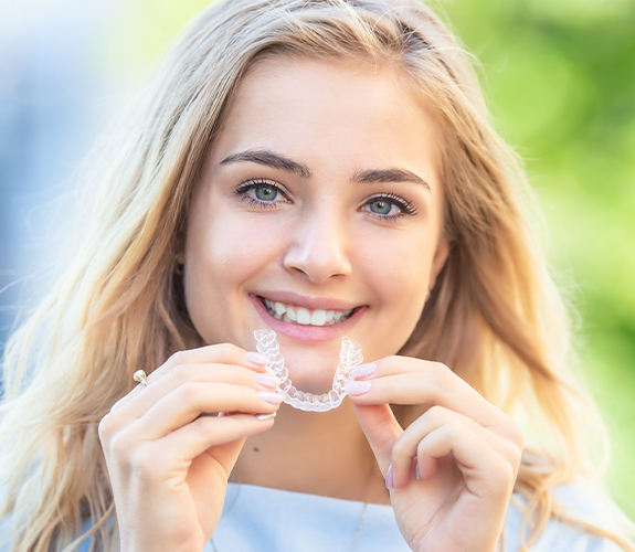 Smiling woman placing Invisalign clear braces