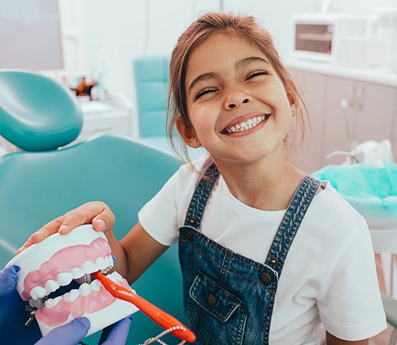 Young girl practicing tooth brushing during children's dentistry checkup