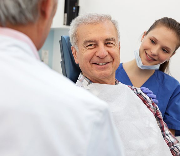 Dentist and dental team member discussing advanced periodontal procedures with patient