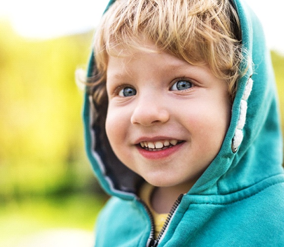 Little boy in hoodie smiling with fillings