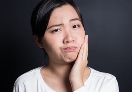 Woman in need of emergency dentistry holding her cheek