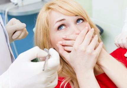 Woman in need of sedation dentistry covering her mouth