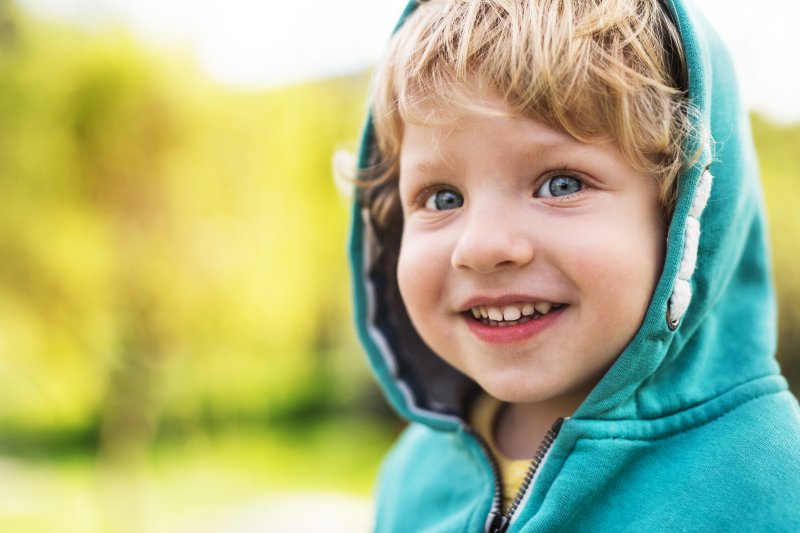 One-year-old boy with emerging teeth outside and smiling