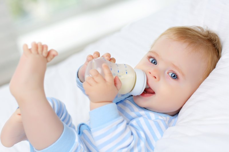 Little boy in striped shirt feeding on bottle
