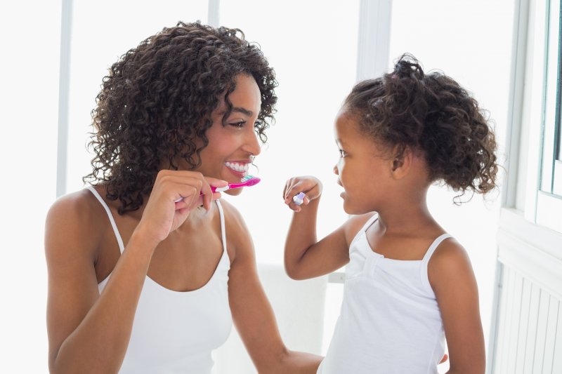 Mother and daughter happily brushing their teeth