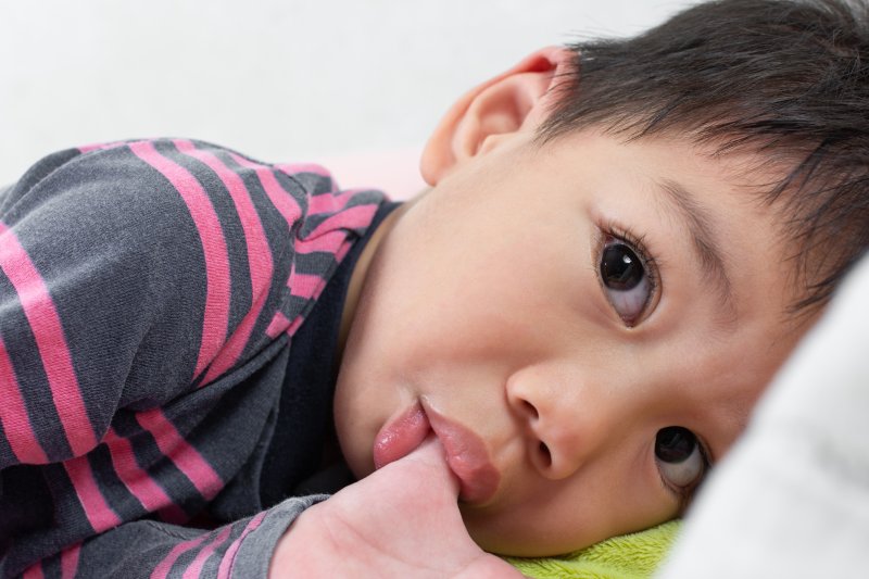 Little boy laying down and sucking his thumb