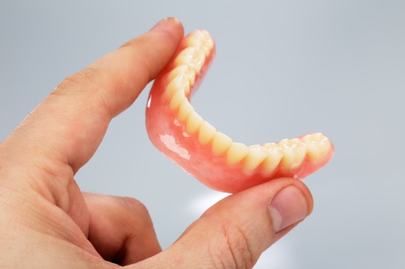 person holding a lower denture