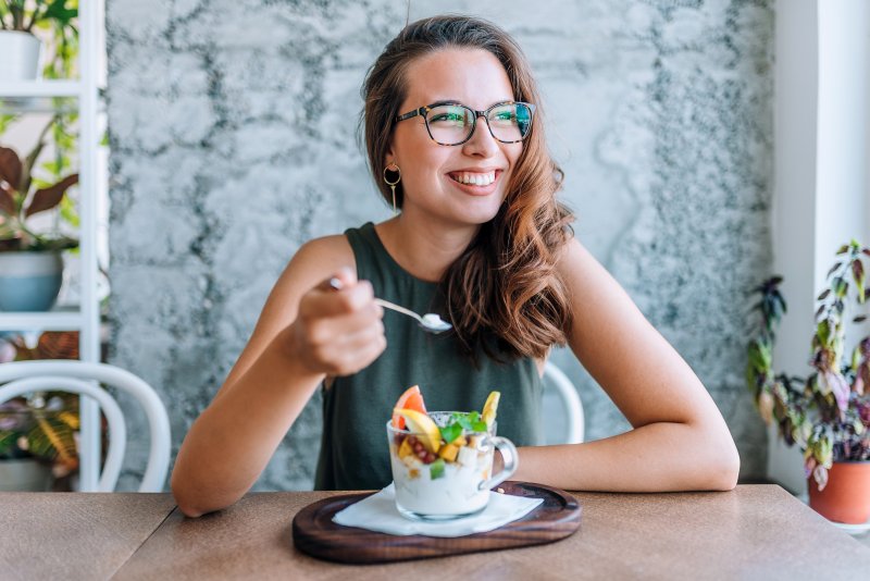 a woman eating a bowl of yogurt and fruit