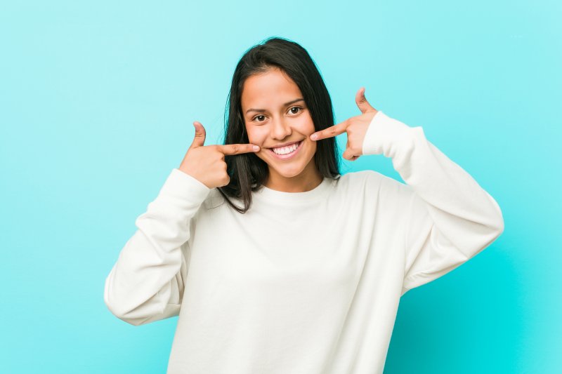 a woman pointing at her new and improved smile