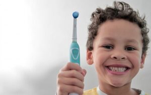 A young boy holding an electric toothbrush